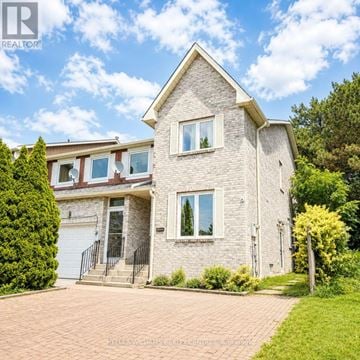Richmond Hill (North Richvale) townhouse for rent - A house with a brick facade and a white garage door is surrounded by greenery.