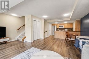 Ottawa townhouse for rent - A living room with a staircase and a kitchen area in the background.