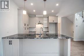 Arnprior townhouse for rent - A kitchen with a marble countertop and white cabinets.