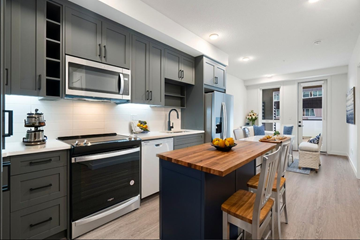 Calgary apartment for rent - A modern kitchen with dark grey cabinets and a wooden island.