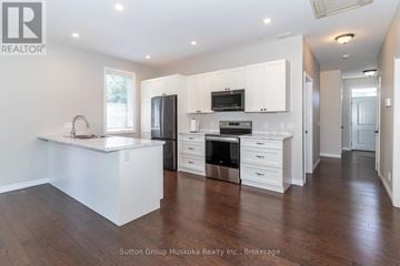 Huntsville (Chaffey) house for rent - A kitchen with white cabinets and a wooden floor.