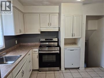 Sarnia apartment for rent - A kitchen with white cabinets and a black stove top oven.