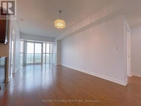 Mississauga (City Centre) condo for rent - A large, empty room with wooden floors and a chandelier hanging from the ceiling.