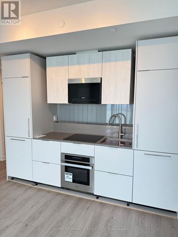 Mississauga (Mississauga Valleys) condo for rent - A modern kitchen with white cabinets and a flat screen TV above the sink.