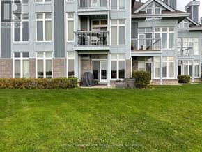 Collingwood condo for rent - A large, multi-story residential building with a green lawn in front.