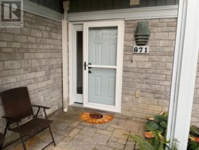Collingwood condo for rent - A chair sits on a patio in front of a door with the number 871 on the wall.