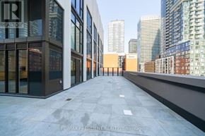 Toronto (Waterfront Communities) condo for rent - A long concrete walkway leads to a building with a glass facade.