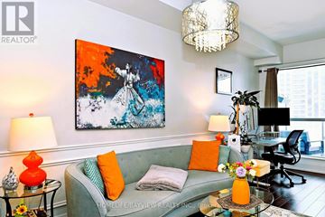 Toronto (Willowdale East) condo for rent - A living room with a grey couch, a painting on the wall, and a glass table with a vase of flowers on it.