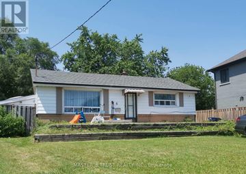 Toronto (L'amoreaux) apartment for rent - A house with a white siding and a grey roof is surrounded by a wooden fence and has a small garden in front.