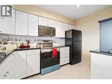 Burnaby apartment for rent - A kitchen with white cabinets and a black fridge.