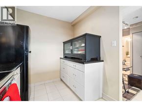 Burnaby apartment for rent - A black fridge sits next to a white cabinet with a television on top.