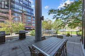 Toronto (Niagara) condo for rent - A patio with a table and chairs is surrounded by a fence and trees.