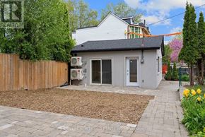 Toronto (Greenwood-Coxwell) apartment for rent - A small house with a grey roof and a grey door is surrounded by a wooden fence.
