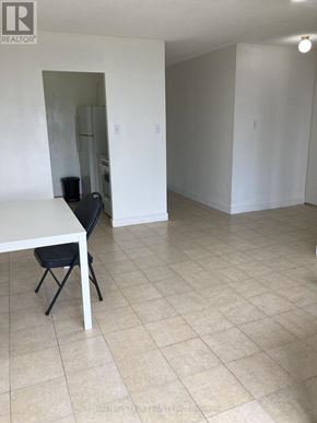 Toronto (Yorkdale-Glen Park) condo for rent - A white table with a black chair is in a room with white walls and tile flooring.