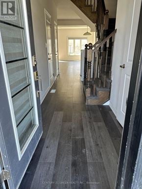 Brantford townhouse for rent - A hallway with a wooden floor and a staircase with a metal railing.
