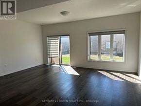 Brantford townhouse for rent - A room with wooden floors and a window showing a view of a building.