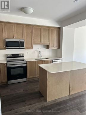 Brantford townhouse for rent - A kitchen with wooden cabinets and a white island.