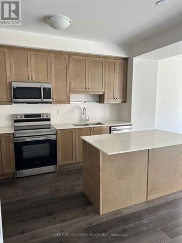Brantford townhouse for rent - A kitchen with wooden cabinets and a white island.
