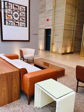 Toronto (Waterfront Communities) condo for rent - A room with a white chair, a brown chair, a white table and a white ottoman.