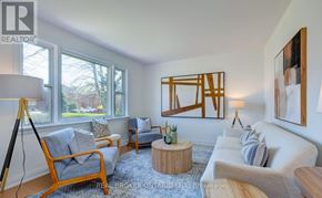 Toronto (Clairlea-Birchmount) apartment for rent - A living room with a grey couch, a wooden chair, a wooden table, and a painting on the wall.