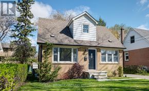 Toronto (Clairlea-Birchmount) apartment for rent - A house with a grey roof and a black door is surrounded by greenery.