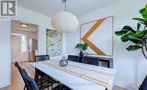 Toronto (Clairlea-Birchmount) apartment for rent - A dining room with a white table and chairs, a hanging light fixture, and a large plant.