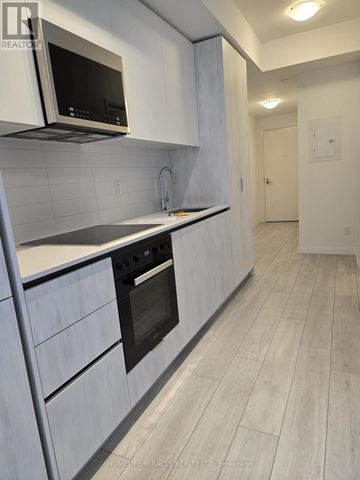 Toronto (Waterfront Communities) condo for rent - A modern kitchen with white cabinets and a black microwave.