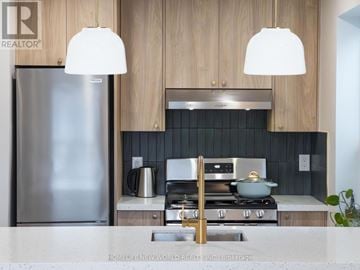 Toronto (South Riverdale) apartment for rent - A modern kitchen with a stainless steel refrigerator and a stove top oven.