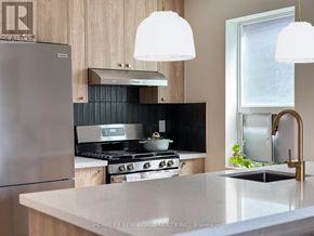 Toronto (South Riverdale) apartment for rent - A modern kitchen with a stainless steel refrigerator and a black backsplash.