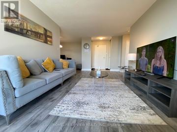 Markham (Thornhill) condo for rent - A living room with a grey couch and a large painting on the wall.