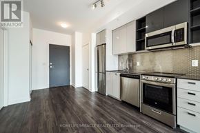 Toronto (York University Heights) condo for rent - A modern kitchen with dark wood floors and stainless steel appliances.