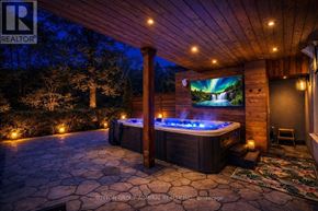 Toronto (Lansing-Westgate) apartment for rent - A hot tub sits in the middle of a stone patio under a lit-up wooden pergola.