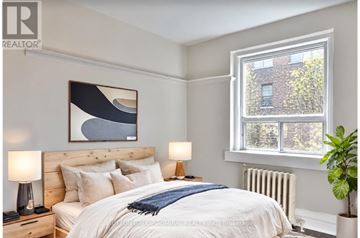 Toronto (Little Portugal) multi-family for rent - A bedroom with a large bed, a window, and a plant.