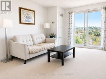 Toronto (Eglinton East) condo for rent - A living room with a white sofa, a black coffee table, and a painting on the wall.