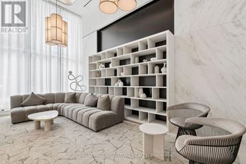 Toronto (Regent Park) condo for rent - A modern living room with a grey sofa, a white coffee table, and a white shelf with a lamp on top.