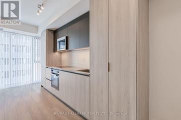 Toronto (Waterfront Communities) condo for rent - A modern kitchen with wooden cabinets and a microwave above the stove.