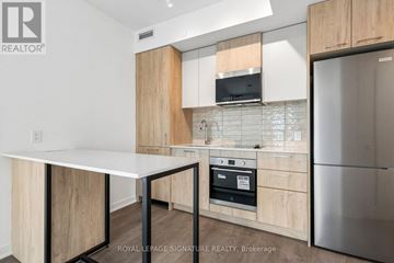 Toronto (Regent Park) condo for rent - A kitchen with a white table and wooden cabinets.