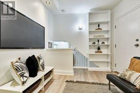 Toronto (The Beaches) multi-family for rent - A living room with a black couch and a television on the wall.