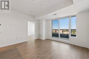 Mississauga (Central Erin Mills) condo for rent - A spacious room with wooden flooring and a large window overlooking a cityscape.