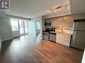 Toronto (South Parkdale) condo for rent - A kitchen with wooden floors and stainless steel appliances.