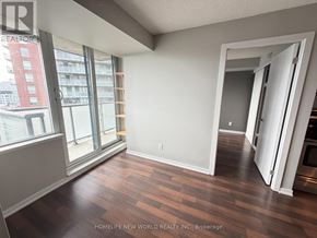 Toronto (South Parkdale) condo for rent - A room with wooden floors and a view of a cityscape through large windows.