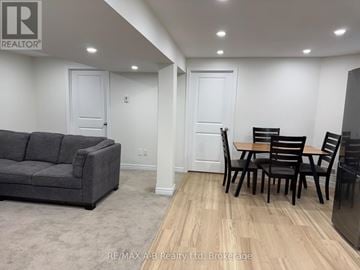 Woodstock (Woodstock - North) apartment for rent - A living room with a grey couch, wooden dining table and chairs, and a kitchenette in the background.