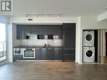 Toronto (Bayview Village) condo for rent - A modern kitchen with dark grey cabinets and a wooden floor.
