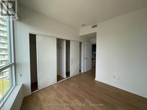 Toronto (Bayview Village) condo for rent - A room with white walls and wooden floors, with a window on the left side.