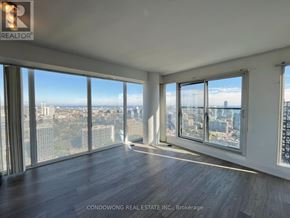 Toronto (Moss Park) condo for rent - A large, empty room with a view of the cityscape outside the windows.