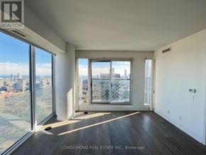 Toronto (Moss Park) condo for rent - A large, empty room with a view of the cityscape outside the windows.
