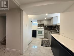 Oshawa (Centennial) apartment for rent - A kitchen with a black fridge and white cabinets.