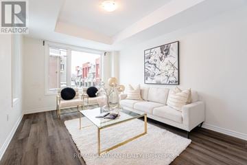 Pickering townhouse for rent - A living room with a white couch, a glass coffee table, and a large abstract painting on the wall.