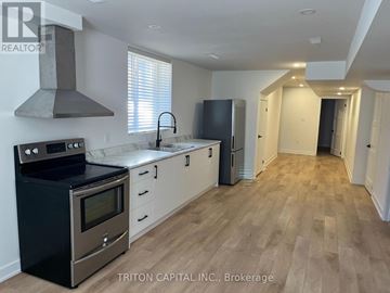 Barrie apartment for rent - A kitchen with a black stove top oven, white cabinets, and a black refrigerator.