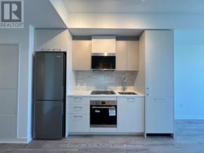 Toronto (Regent Park) condo for rent - A kitchen with a black refrigerator and white cabinets.